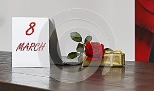 Womens Day background with of red roses gift box, Lettering with date March 8, open laptop computer, copy space.