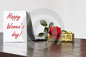 Womens Day background with of red roses gift box, Lettering with date March 8, open laptop computer, copy space.