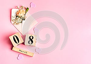 Womens day composition. 8 march wooden calendar with flowers in an envelope on the pink background. Copy space, top view