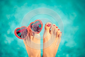 Womens feet with red pedicure against blue water background