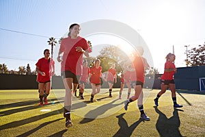 Womens Football Team Run Whilst Training For Soccer Match On Outdoor Astro Turf Pitch