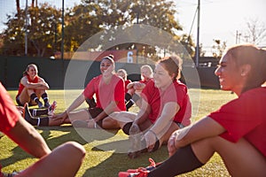 Womens Football Team Stretching Whilst Training For Soccer Match On Outdoor Astro Turf Pitch