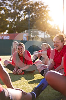 Womens Football Team Stretching Whilst Training For Soccer Match On Outdoor Astro Turf Pitch