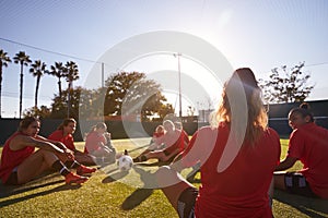 Womens Football Team Stretching Whilst Training For Soccer Match On Outdoor Astro Turf Pitch