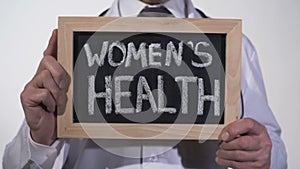 Womens health written on blackboard in gynecologist hands, reproductive medicine