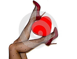 Womens legs in black tights and maroon high heel shoes holding red heart ballon