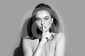 Womens secrets. Woman showing secret sign. Female with finger in mouth. Closeup portrait of young woman is showing a