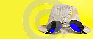 Womens summer straw hat with a brim, blue rounded sunglasses on yellow background