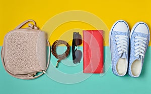 Womenshoes and fashion accessories on a blue yellow pastel background. Sneakers, a bag, a purse, a belt, sunglasses. Spring su photo