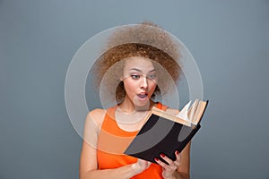 Wondered curly young female reading book