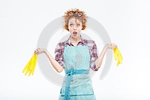 Wondered housewife holding yellow gloves in both hands