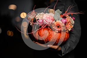 wonderful bouquet of flowers in pumpkin on female hand. Decoration for thanksgiving day and halloween