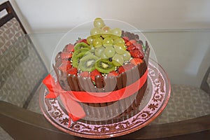 Wonderful cake filled with chocolate and decorated with strawberries, green grapes, kiwi and chocolate bars in palisade