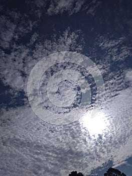 A wonderful close up of an exceptional view of an delightful pattern of white clouds in dark blue sky with shining sun