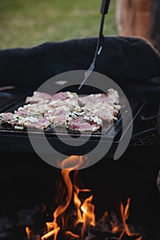 Wonderful detail of grilling pork neck meat on a granite stone laid on the heat of the fire. Meat sprinkled with salt, basil,