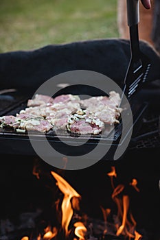 Wonderful detail of grilling pork neck meat on a granite stone laid on the heat of the fire. Meat sprinkled with salt, basil,