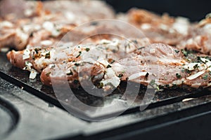 Wonderful detail of grilling pork neck meat on a granite stone laid on the heat of the fire. Meat sprinkled with salt, basil,