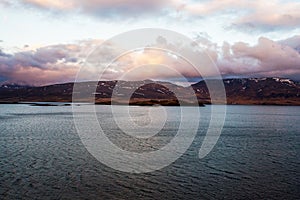 Wonderful icelandic nature landscape. High mountains, snow, mountain riwer and green grassland.