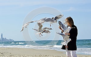 Contento salutare maturo una donna mano alimentazione gabbiani birdwatching sul Spiaggia 