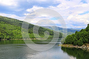 Wonderful lake with clouds and a lot of vegetation all around. Beautiful valley. photo