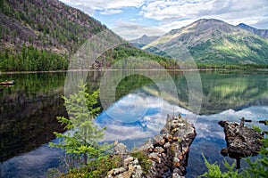 Wonderful lake wide panorama. Scenic summer landscape, mountains and blue cloudy sky at background. Eastern Sayan