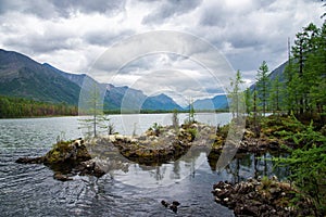 Wonderful lake wide panorama. Scenic summer landscape, mountains and blue cloudy sky at background. Eastern Sayan