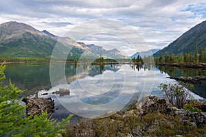 Wonderful lake wide panorama. Scenic summer landscape, mountains and blue cloudy sky at background. Eastern Sayan