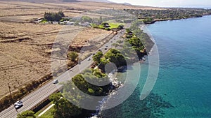Wonderful photography of various cars traveling on the road between volcanic landscapes and ocean shore on island maui
