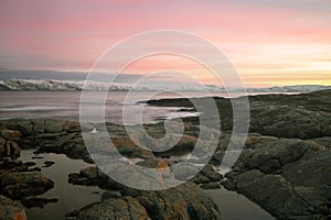 Wonderful purple sunset over the sea. Fakrutny stone shore in the foreground. Arctic Ocean