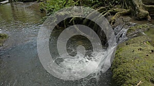 Wonderful rapid small waterfall flowing into the pond in the natural park. Freshness water stream in tropical jungle during summer