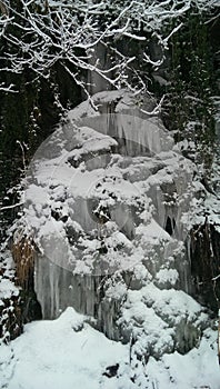 Wonderful small waterfall icebound covered with snow in wintertime
