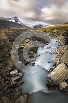 Wonderful sun lit autumn landscape with wild river raging down