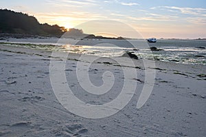 Wonderful sunset on a lonely beach at low tide, single boat on the sand, peaceful mood