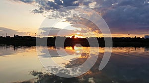 Wonderful sunset over the city horizon with reflection on the calm lake water in a silent summer evening