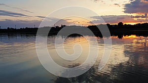 Wonderful sunset over the city horizon with reflection on the calm lake water in a silent summer evening