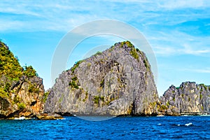 Wonderful view of the blue sea, the sea cliffs covered with plants and a bright blue sky. El Nido Palawan Philippines