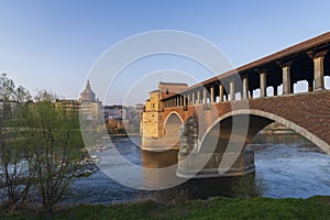 Wonderful view of covered bridge and Pavia Cathedral in background at sunny day in Pavia