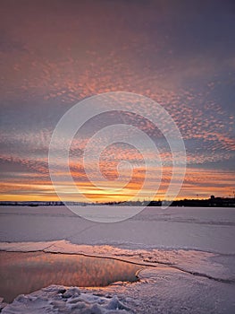 Wonderful winter sunset above the frozen lake, vertical background