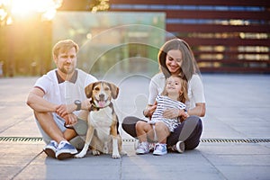 Wonderful young family is resting sitting on the ground.