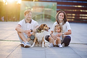 Wonderful young family is resting sitting on the ground.