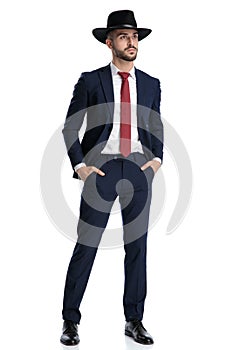 Wondering businessman looking away with both hands in pockets