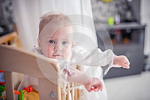 Wondering little girl standing in the crib