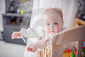 Wondering little girl standing in the crib