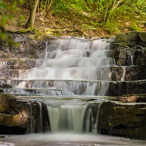 Wonderous waterfall in rocks in a fall forest photo