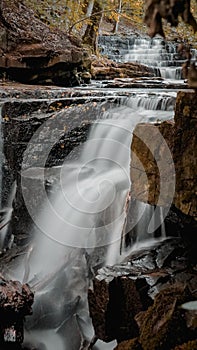 Wonderous waterfall in rocks in a fall forest photo