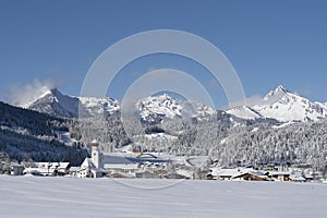wondrous freshly snow-covered tourism village of heiterwang with wispy clouds on the hahnenkamm mountain range