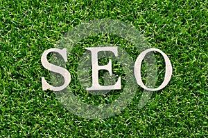Wood alphabet in word SEO Abbreviation of search engine optimization on artificial green grass background