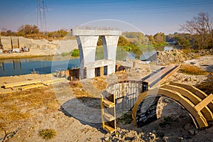 Wood arch molds at building site, huge pole in foundation with metal piles, construction of concrete-reinforced bridge pillars