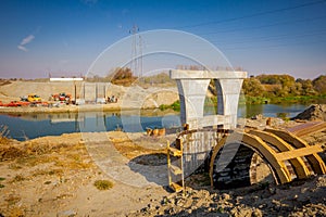 Wood arch molds at building site, huge pole in foundation with metal piles, construction of concrete-reinforced bridge pillars