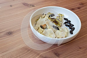 Wood background with bowl aligned right, pieces of skin and seeds of an eaten cherimoya fruit